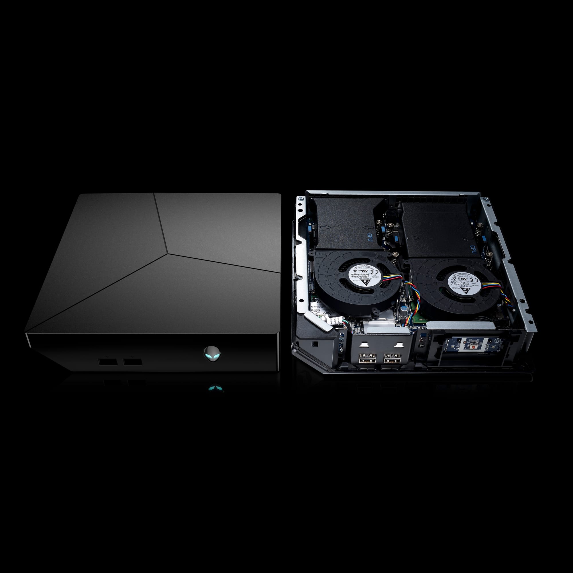 Two Alienware Steam Machine game console desktop computers (codename Coral SM), one with chassis and one with external chassis removed to reveal internal components, sitting side-by-side, shown on black background.